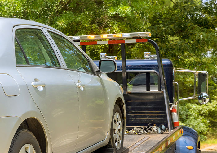 Silver car being towed on a flatbed truck, symbolizing enforcement of a restraining order against MIL after 29 years of marriage.