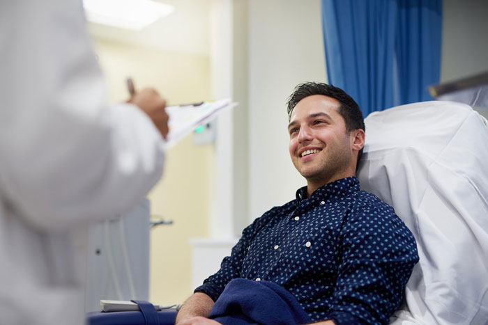 Smiling man in a hospital bed talking with a doctor after telling his family he doesn&rsquo;t want a funeral.