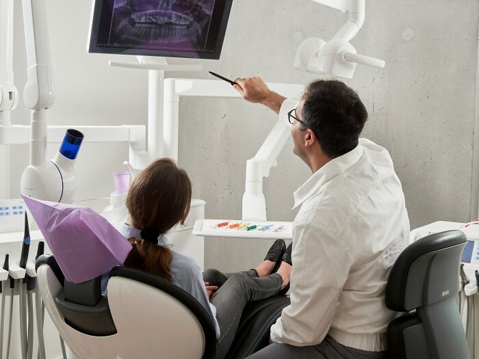 Dentist reviewing dental X-ray with a patient in a clinic, highlighting moments when patients coming off anesthesia were funny.