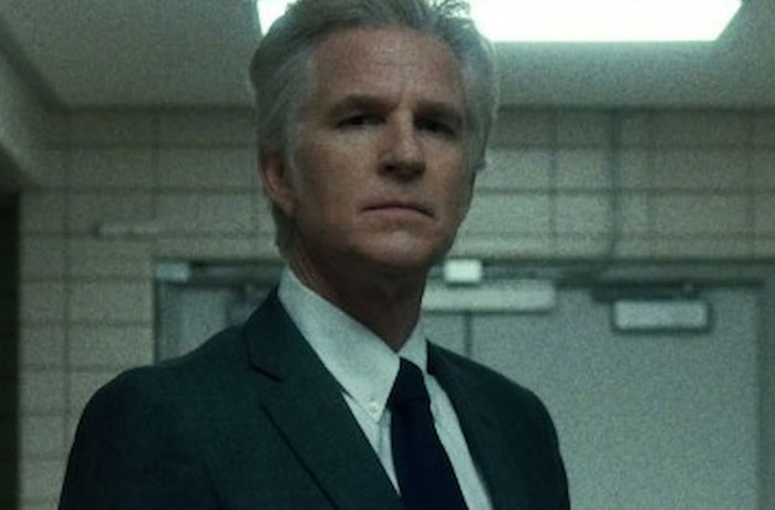 Man in suit with serious expression in dimly lit room, related to funny things parents said watching Stranger Things Season 5