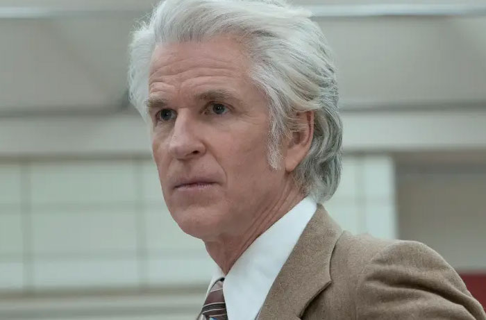 Older man with white hair wearing a brown suit and tie, appearing thoughtful while watching Stranger Things season 5.