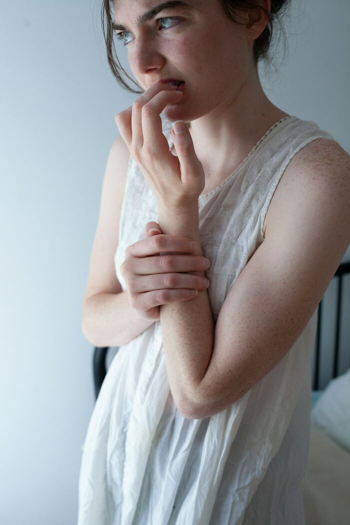 Young woman in a white dress appearing thoughtful and anxious, reflecting on relationships and emotions about women.