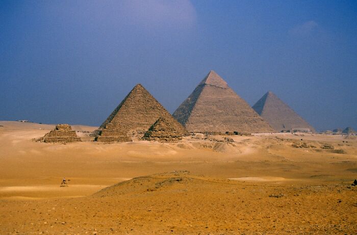 Ancient pyramids in desert under blue sky, symbolizing mysteries that remain unsolved across history.
