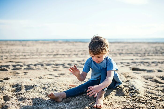 Child playing alone on the beach representing shocking secrets people trust strangers online with but keep private.
