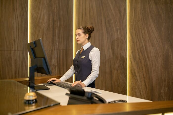 Receptionist in uniform working at the front desk, illustrating men being men and women suffering stories in 2025.