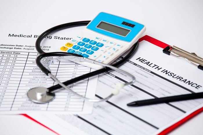 Calculator and stethoscope on medical billing statements and health insurance forms, revealing hidden dark secrets.