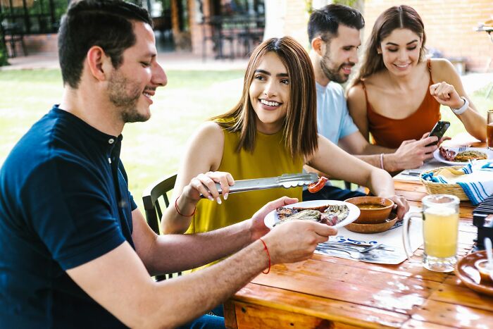 Group of friends enjoying grilled food outdoors, highlighting everyday things that are more dangerous for health than realized.