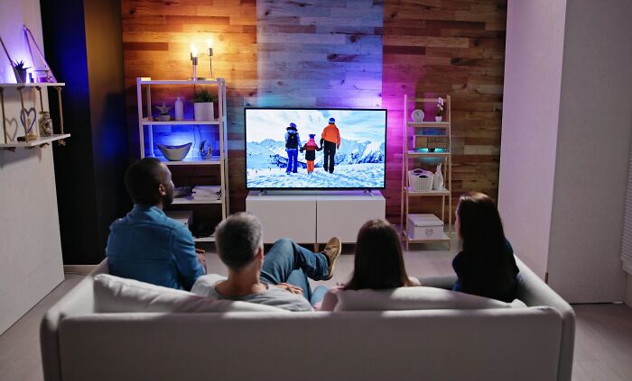 Four people watching television together in a living room, illustrating snobbish behavior discussed in online shaming content.