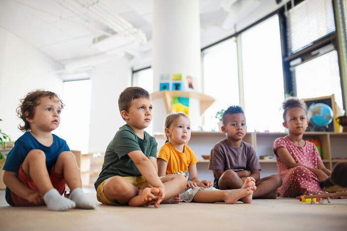 Group of diverse children sitting on the floor in a bright classroom, representing bizarre and unbelievable names given to kids.