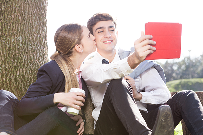 Young couple outdoors taking a selfie, contrasting with the bride walking out after learning groom cheated with her mom.