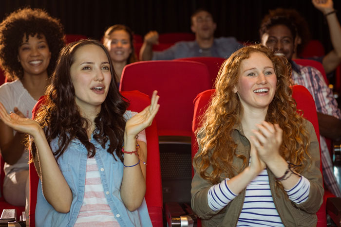 Two women happily clapping in a theater, illustrating a lady’s unpunctual friend painting nails before event. Two women happily clapping in a theater, illustrating a lady’s unpunctual friend painting nails before event.