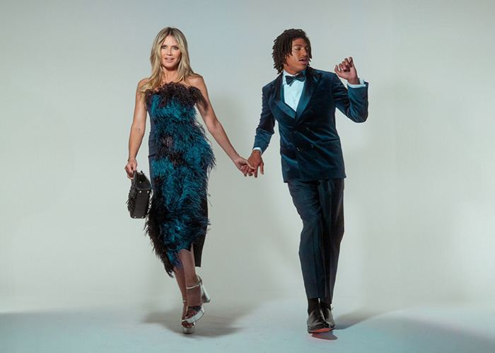 Heidi Klum poses in a feathered dress holding hands with her son in a blue velvet suit for Elle cover photo.