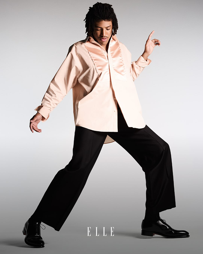 Young male model posing on Elle cover, sparking discussion among fans about model material and fashion standards.