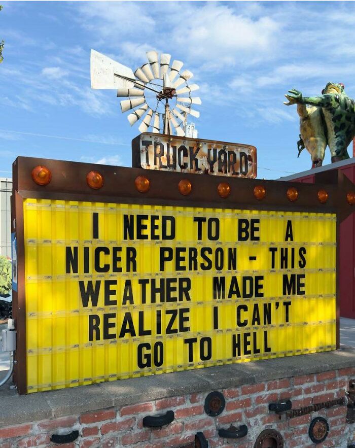 Funny memes sign at truck yard with humorous text about weather and being a nicer person on a bright winter day.
