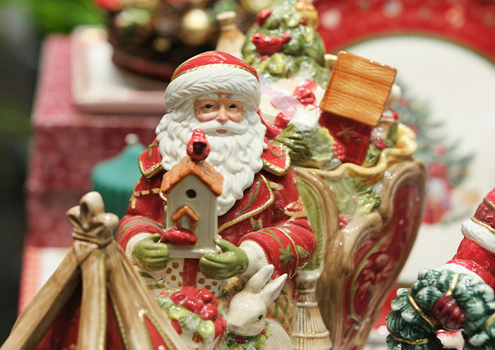 Festive Santa Claus figurine holding a birdhouse surrounded by holiday decorations and vintage ornaments.