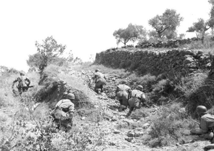 Black and white photo of soldiers climbing a rocky hill, illustrating bizarre facts from history in wartime settings.