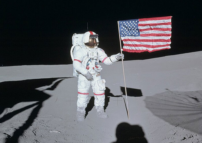 Astronaut in a spacesuit holding an American flag on the moon, illustrating bizarre facts from history and space exploration.