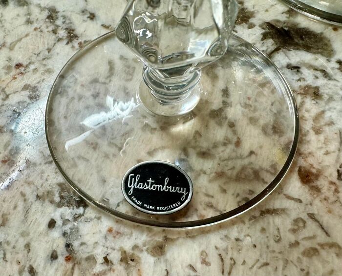 Close-up of a glass base with a Glastonbury label showing a small design mistake on a textured surface.