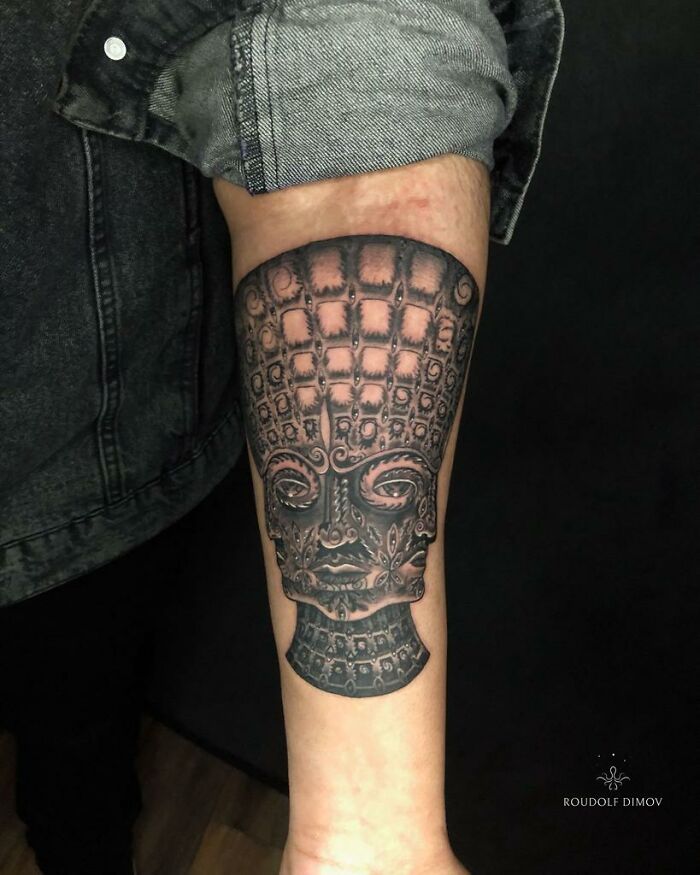 Intricate psychedelic tattoo on forearm featuring a detailed, surreal face design capturing attention and curiosity.