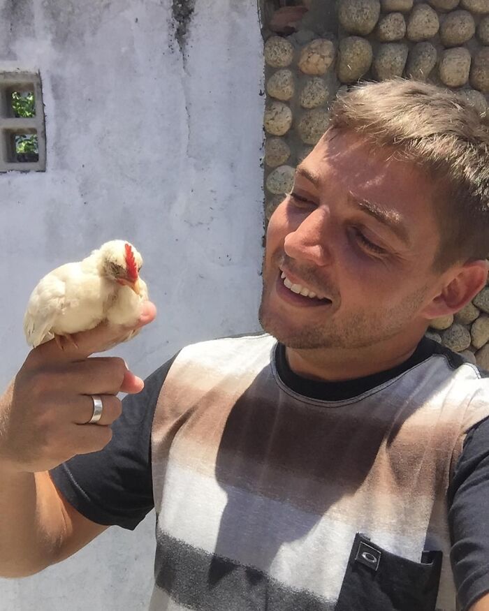 Man smiling while holding a small bird, showing a close bond with a wild vulture in an outdoor setting.