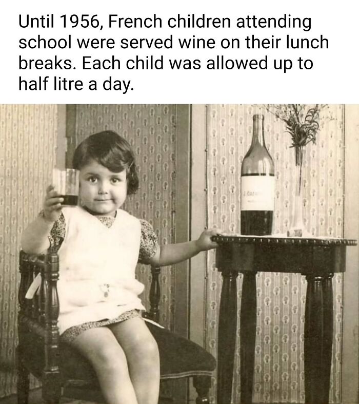 Vintage photo of a young child holding a glass of wine, highlighting historical school wine serving practices in France.