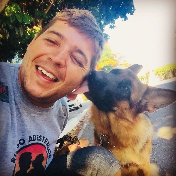 Man smiling outdoors with a German shepherd dog, highlighting a close human and wild vulture bond like a dog with wings