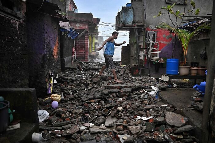 Man walking across rubble in a narrow alleyway, showcasing street life and urban scenes in Mumbai.