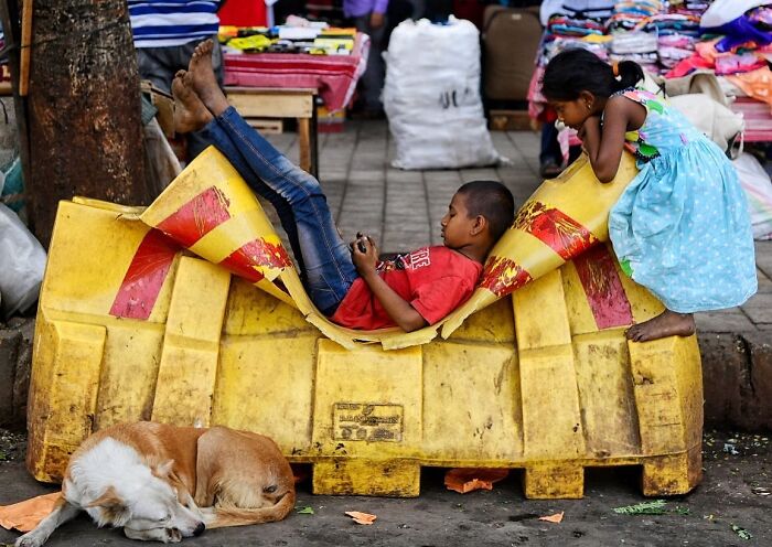 Two children playing on a street in Mumbai while a dog sleeps nearby, capturing everyday life moments.