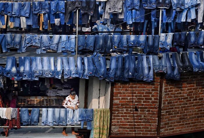 Rows of blue jeans hanging to dry on lines above a street, capturing everyday life in Mumbai street photography.