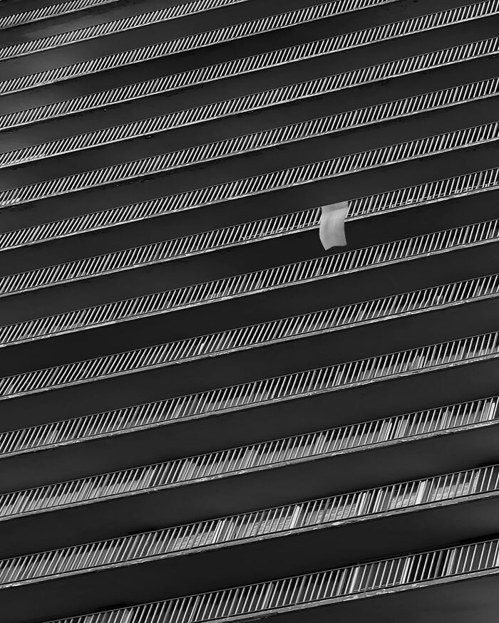 Minimalist black and white photo of repetitive building balconies with a single towel hanging, showcasing minimalist photography art.