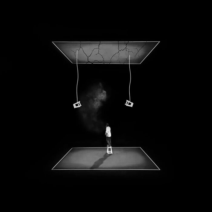 Minimalist black and white photo with a person on a stool under a c*****d ceiling, showcasing striking minimalism art.