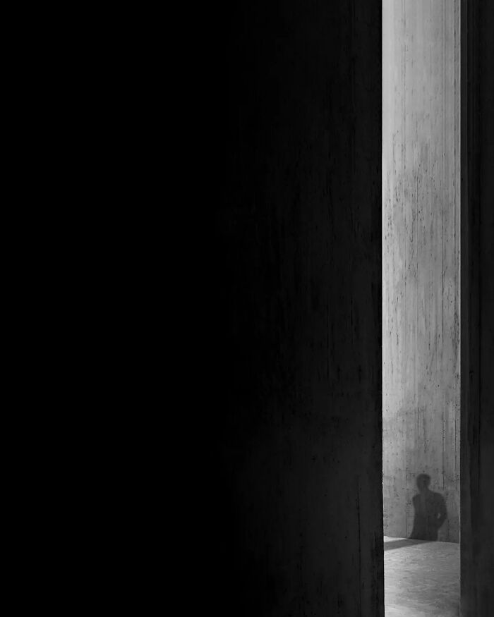 Shadow of a person on a concrete wall in a minimalist space, highlighting the art of minimalism photography.
