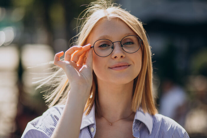 Young woman with glasses outdoors, showcasing fascinating human body features in natural sunlight.