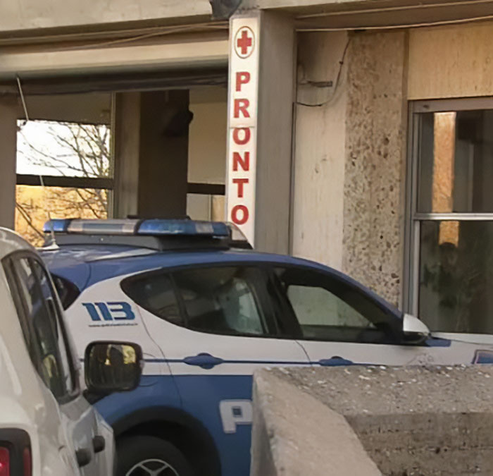 Police car parked outside Italian hospital emergency entrance as town reacts to fatal Christmas dinner incident involving mother and daughter.