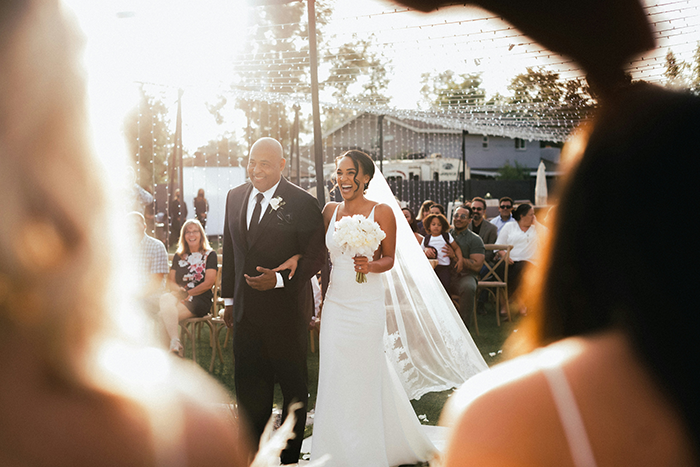 Bride walking down the aisle with father at outdoor wedding ceremony, capturing couple split at altar moment. Bride walking down the aisle with father at outdoor wedding ceremony, capturing couple split at altar moment.