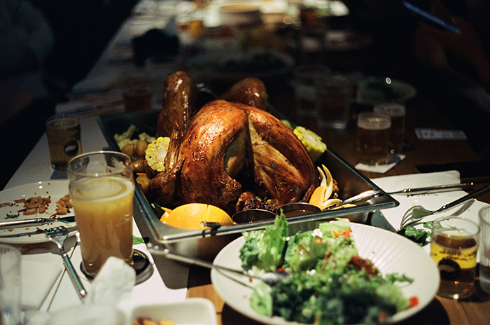 Roast turkey on a table surrounded by drinks and salad, capturing the moment of hunger and family gathering.