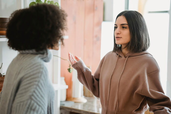 Two women engaged in a serious conversation indoors, illustrating a tense moment related to a Jehovah's Witness mom's birthday celebration.