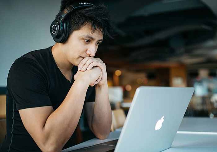 Man wearing headphones, focused on laptop screen, reflecting on mental questions job candidates ask recruiters.