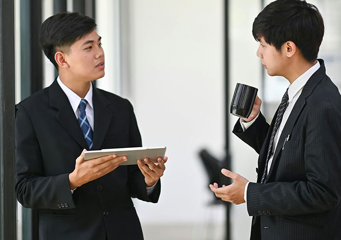 Two men in suits discussing mental questions job candidates asked recruiters during a professional conversation.