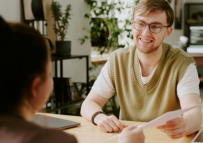 A job candidate asking mental questions during an interview with a recruiter in a modern office setting.