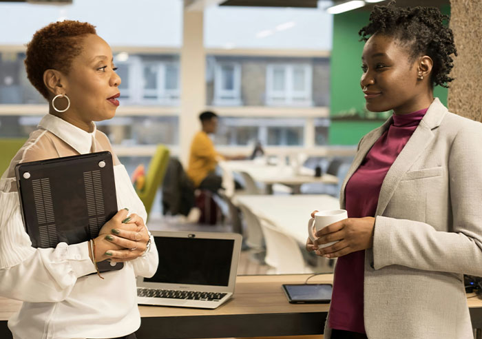 Two professional women in a modern office discussing mental questions job candidates ask recruiters.