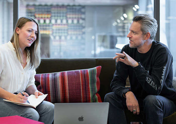 Two professionals engaged in a discussion with a laptop, highlighting job candidates asking recruiters mental questions.