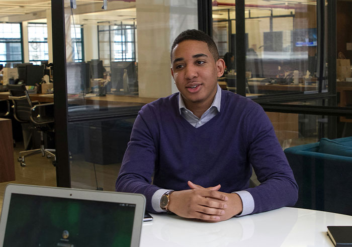 Job candidate asking questions during a recruiter interview in a modern office setting with laptop on the table.