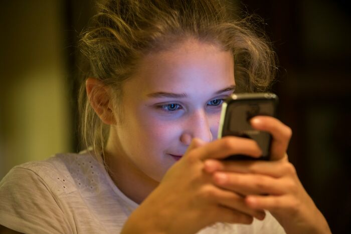 Young woman focused on her phone, reflecting on confessions of the dirtiest, slimiest, backstabbing things done and regretted.