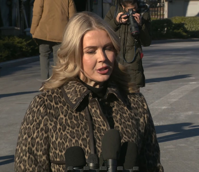 Karoline Leavitt speaking outside, with microphones and a photographer capturing her close-up defended by VF photographer.