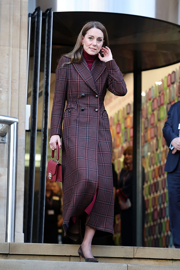 Kate Middleton wearing a long plaid coat and heels during Christmas appearance amid scar and cancer conspiracy theories.