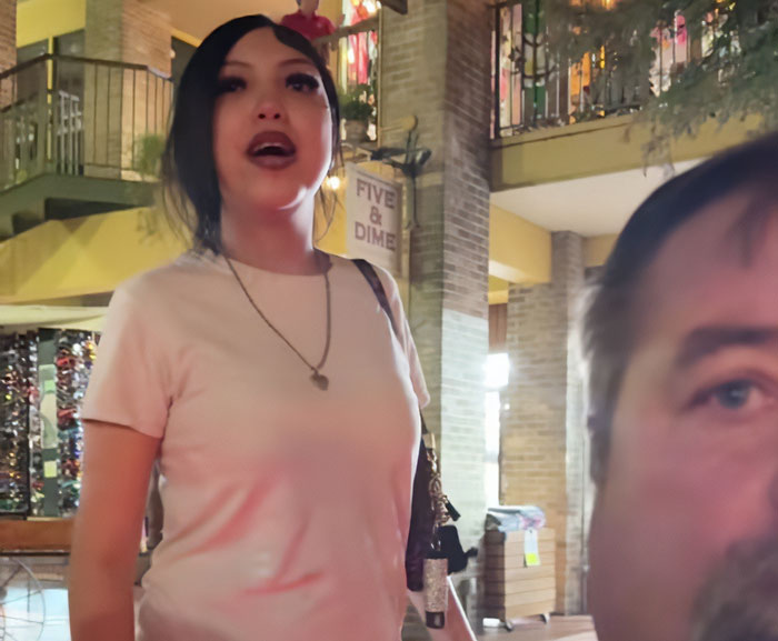 Teen in a pink shirt standing indoors near a brick pillar, related to judge teaching harsh lesson after pepper-spraying tourists on boat. Teen in a pink shirt standing indoors near a brick pillar, related to judge teaching harsh lesson after pepper-spraying tourists on boat.
