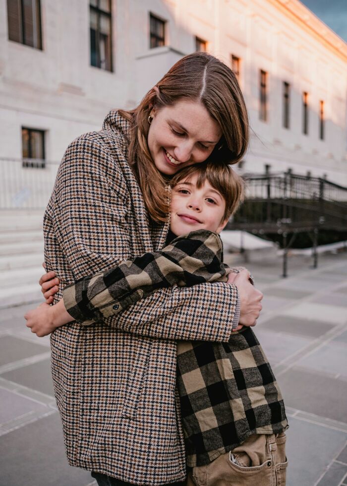 Mother and child sharing a warm hug outdoors, illustrating modern parenting trends and family bonding moments.
