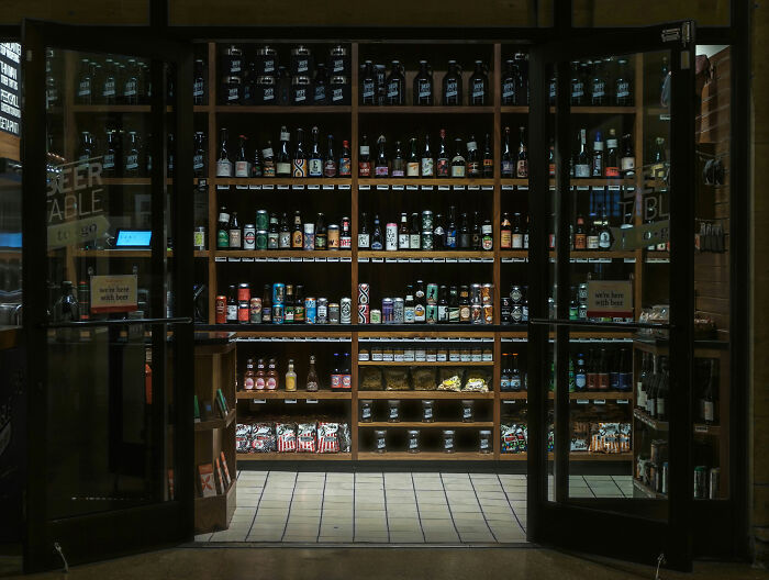 Liquor store shelves filled with various bottles and cans, setting the scene for raccoon raid and bathroom mishap.