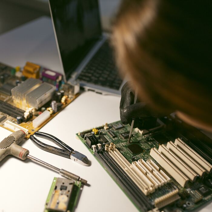 Person repairing a computer motherboard with tools on a white table, illustrating the concept of a painful breakup or final straw in friendship.